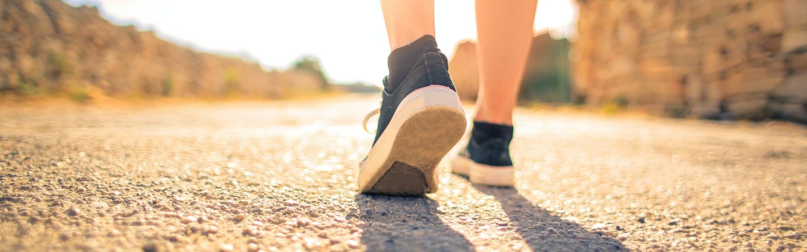 woman walking on pathway under the sun