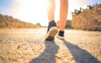 woman walking on pathway under the sun