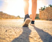 woman walking on pathway under the sun