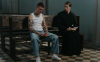 tattooed man sitting beside a priest