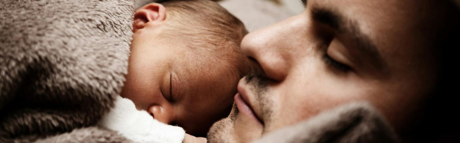 close up of a dad and his little baby sleeping together