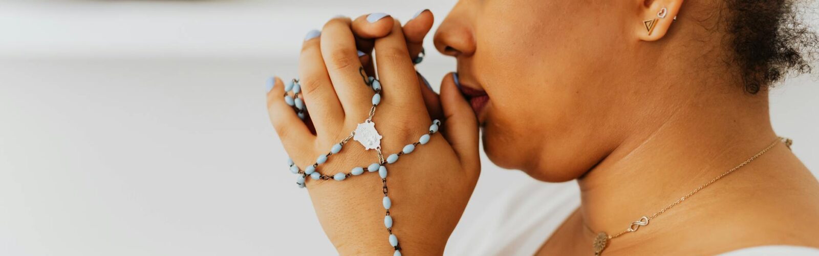 a close up shot of a woman holding a rosary while praying