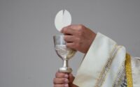 priest holding a chalice and communion bread
