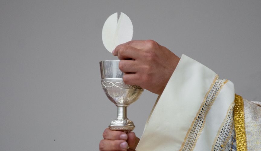 priest holding a chalice and communion bread